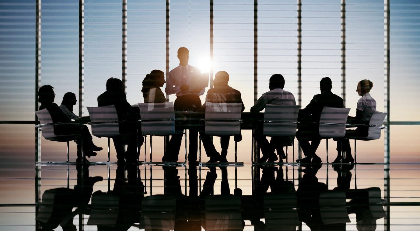 A group of people sitting at a table in front of a window.