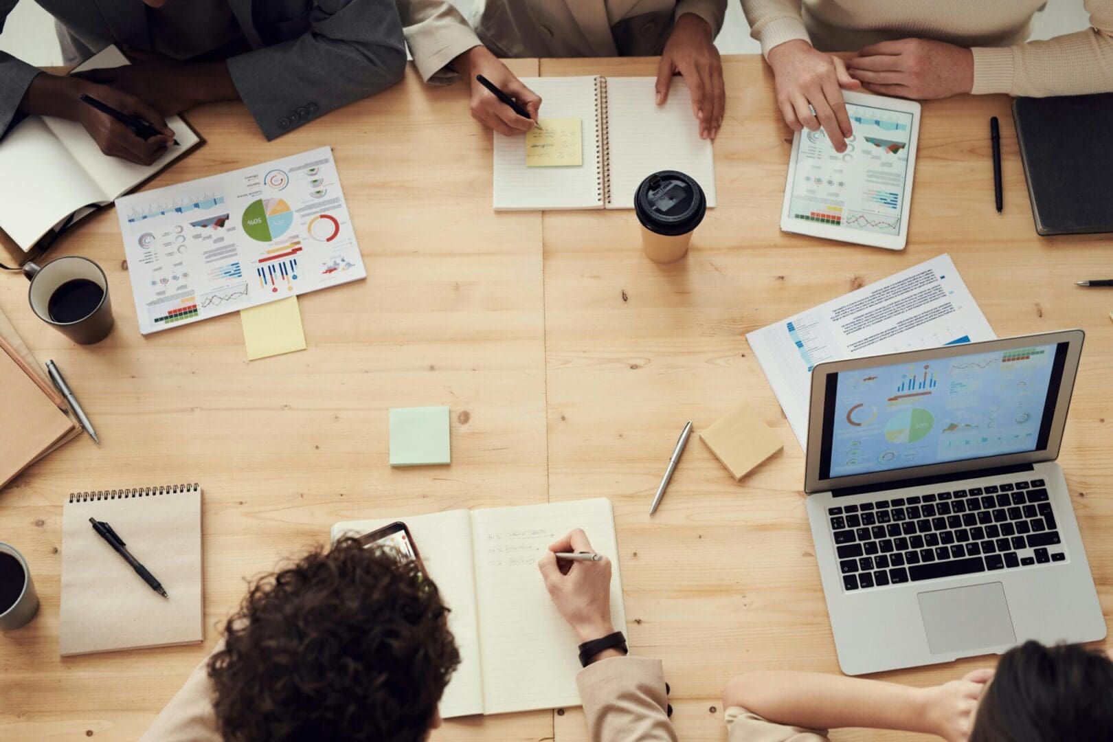 A group of people sitting around a table with papers and laptops.